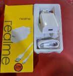 Realme 33W SuperDart Fast Charger Adapter | DeshiBD.com Power up your smartphone in minutes with the Original Realme 33W SuperDart Fast Charger, now available at DeshiBD.com. Designed for blazing-fast and safe charging, this genuine Realme power adapter delivers consistent performance and long-lasting reliability — perfect for all Realme smartphones and VOOC-compatible devices. ⚡ Key Features: ⚙️ 33W SuperDart Fast Charging: Boost your battery from 0% to 100% in record time. 🔋 Wide Compatibility: Works seamlessly with all Realme smartphones and VOOC-enabled devices. 🔒 Multiple Safety Protections: Built-in safeguards against overheating, overvoltage, and short circuits. 🧳 Compact & Portable Design: Lightweight and travel-friendly, perfect for everyday use. 🔌 EU/US Plug Options: Suitable for multiple regions and devices. 🎨 Elegant White Finish: Sleek, premium look that complements your device. 🔋 Product Description: Experience next-level charging with the Realme 33W SuperDart Fast Charger Adapter (Model: VCB3HDEH). Engineered with SuperDart and VOOC fast charging technology, this original Realme adapter ensures rapid and efficient power delivery for your smartphone. With a maximum output of 33W, it delivers high-speed charging while maintaining low temperature and stable current flow. The charger’s intelligent protection system shields your device from electrical hazards, providing a safe and reliable charging experience every time. Its compact, lightweight design makes it perfect for travel, while the durable build quality ensures long-term use. Compatible with a wide range of Realme smartphones, this adapter is ideal for users who need fast, dependable power wherever they go. ⚙️ Technical Specifications: Feature Details Brand Realme Model VCB3HDEH Color White Charging Technology SuperDart / VOOC Fast Charging Input 100–240V~50/60Hz 1.2A Output 5V=2A / 5V–11V~3A Maximum Output Power 33W Plug Type EU/US Compatibility All Realme Smartphones Warranty 3 Months 💡 Why Buy from DeshiBD.com: ✅ 100% Original Realme product ✅ Fast & safe charging with SuperDart technology ✅ Compact design for easy portability ✅ Backed by 3-month official warranty ✅ Best price in Bangladesh 💰 Realme 33W SuperDart Charger Price in Bangladesh: Get the Realme 33W SuperDart Fast Charger Adapter at the best price in Bangladesh from DeshiBD.com. Enjoy genuine quality, ultra-fast charging, and peace of mind with every purchase. ⚡ Charge Faster. Stay Powered. Go Real — only at DeshiBD.com!